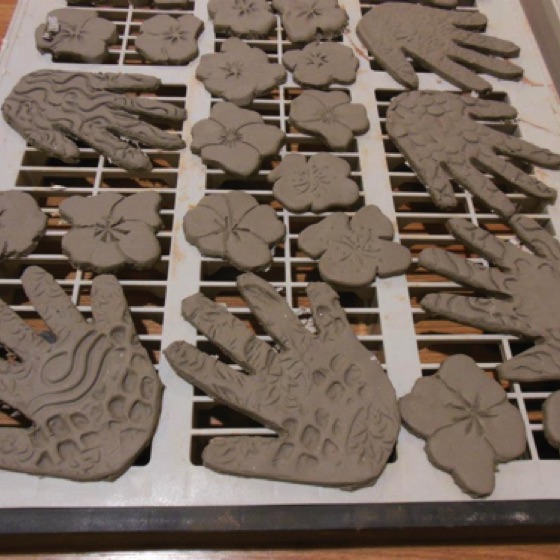 Clay hands and poppies dry prior to being glazed.