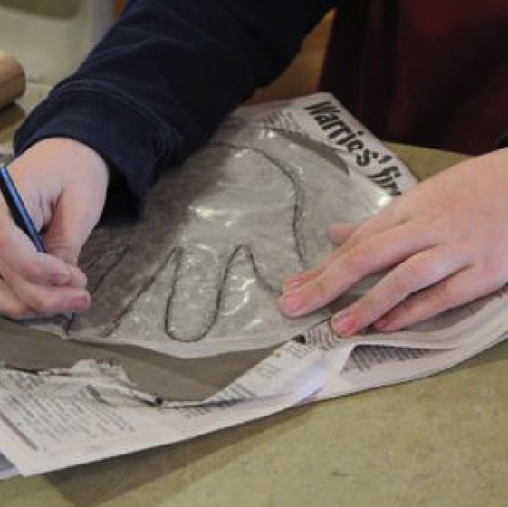 A young artist traces a hand pattern over wet clay to create a tile for the mosaic.
photo courtesy of Piper Nicolosi